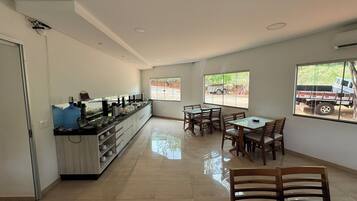 Cozinha espaçosa com bancada comprida, área de jantar com cadeiras de madeira e grandes janelas com vista para o exterior.