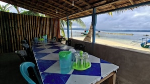 Un comedor cubierto con una mesa a cuadros, sillas y vistas a la playa y al agua.