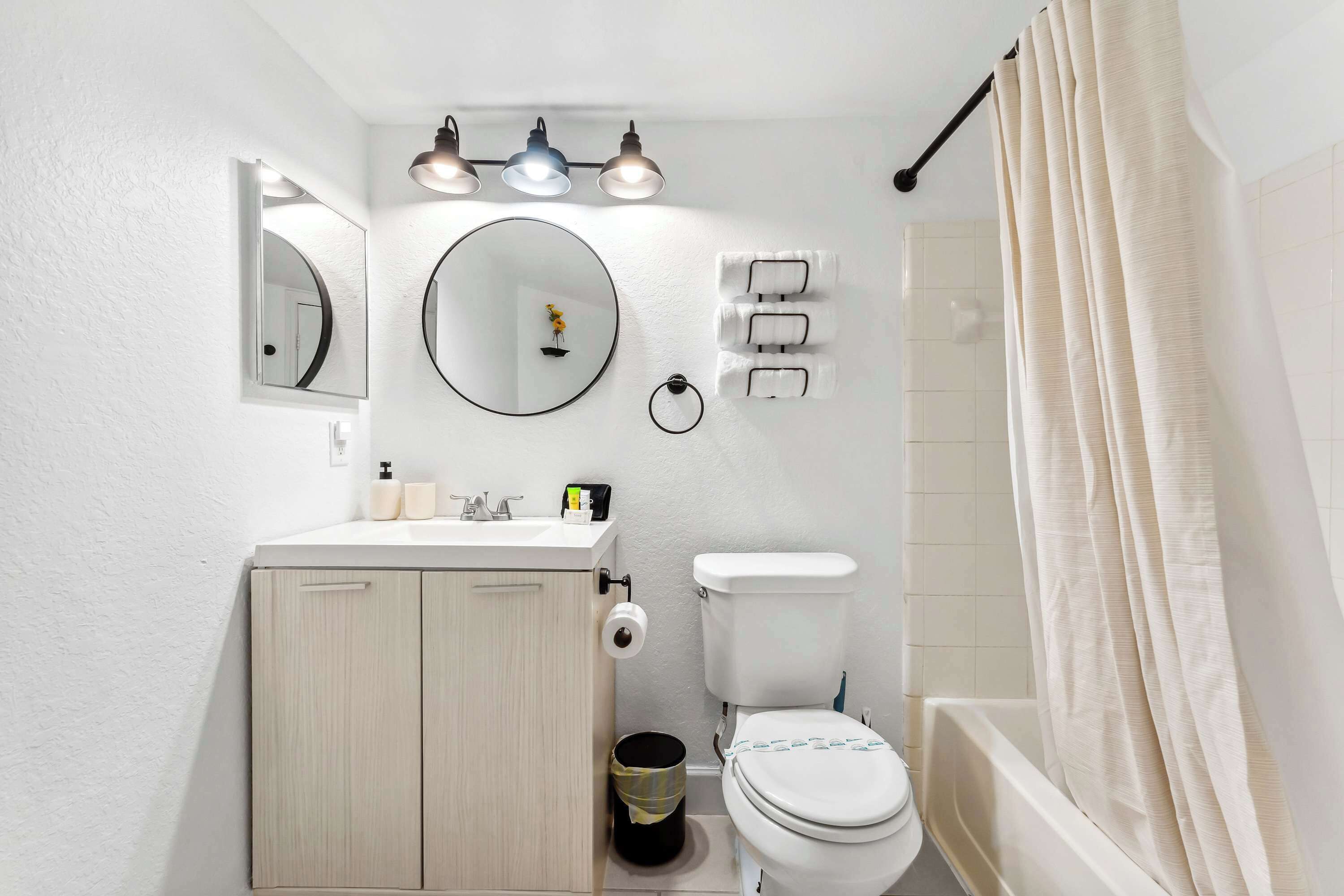 Ein Badezimmer mit Toilette, Waschbecken, Spiegel und Duschvorhang.