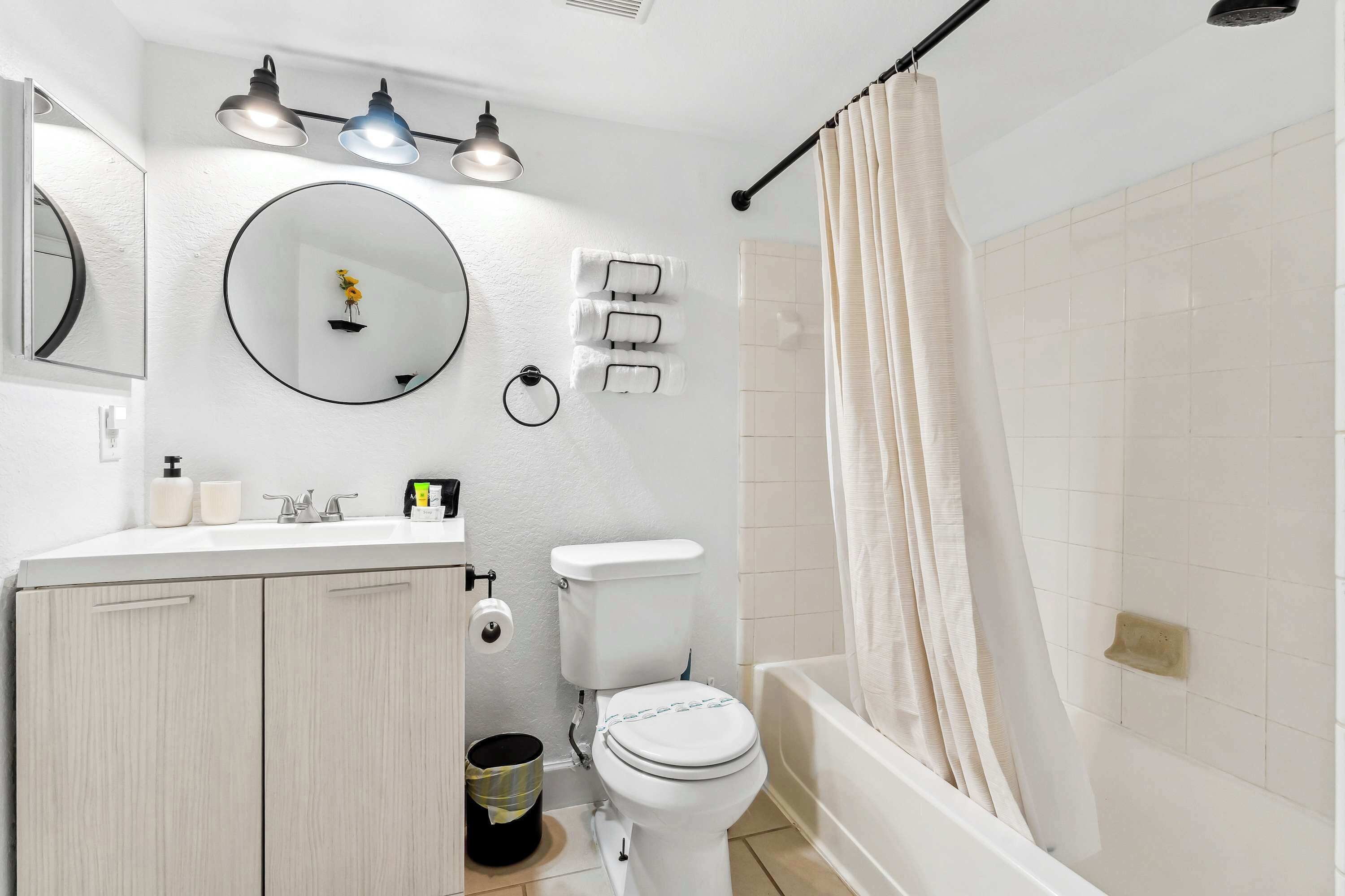 Une salle de bain équipée de toilettes, d’un lavabo, d’un miroir et d’un rideau de douche.