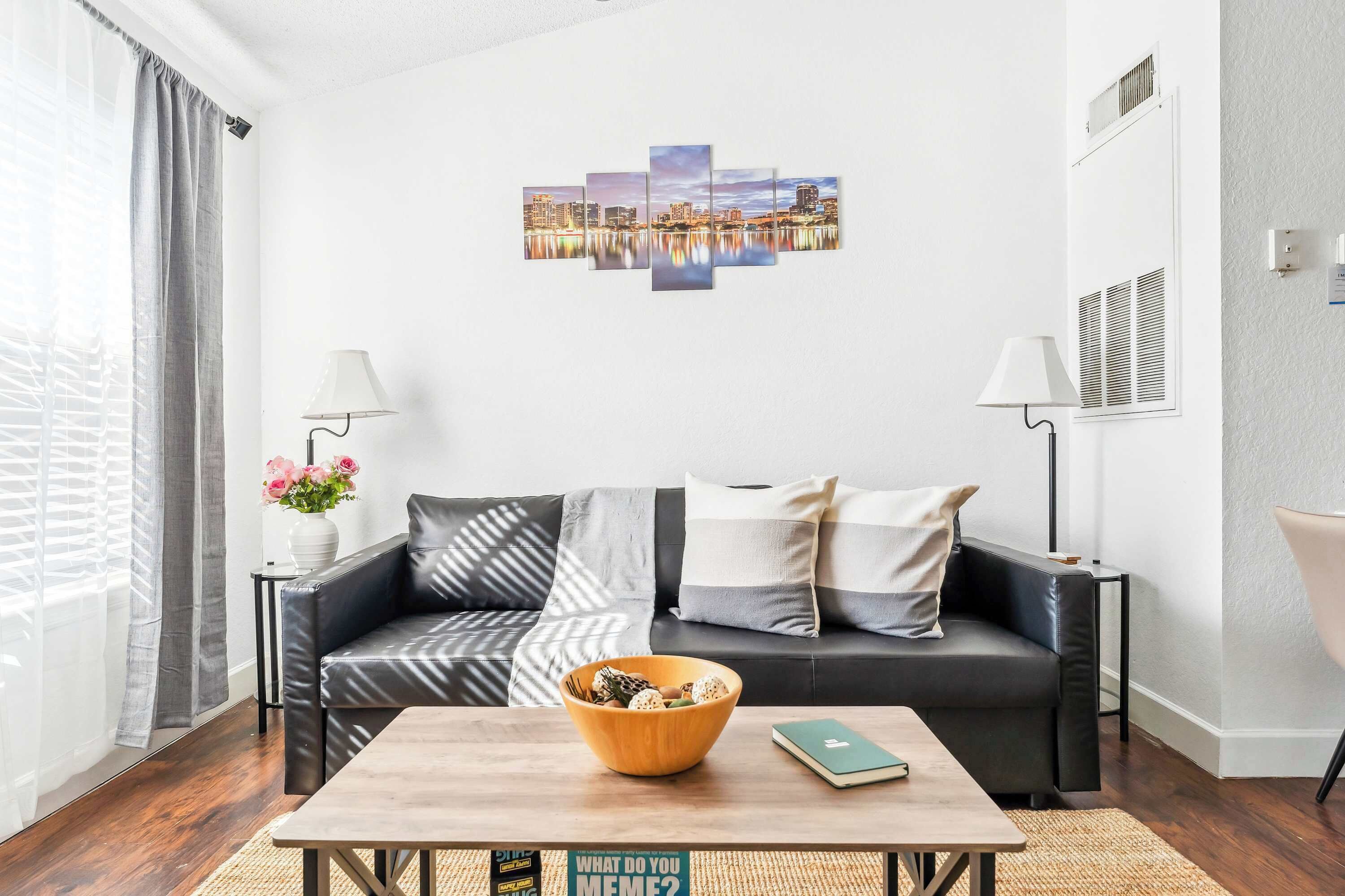A modern living room with a leather sofa, a wooden coffee table, and a cityscape wall art.