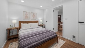 Un dormitorio con cama, mesitas de noche y un cabecero de madera, además de una puerta.