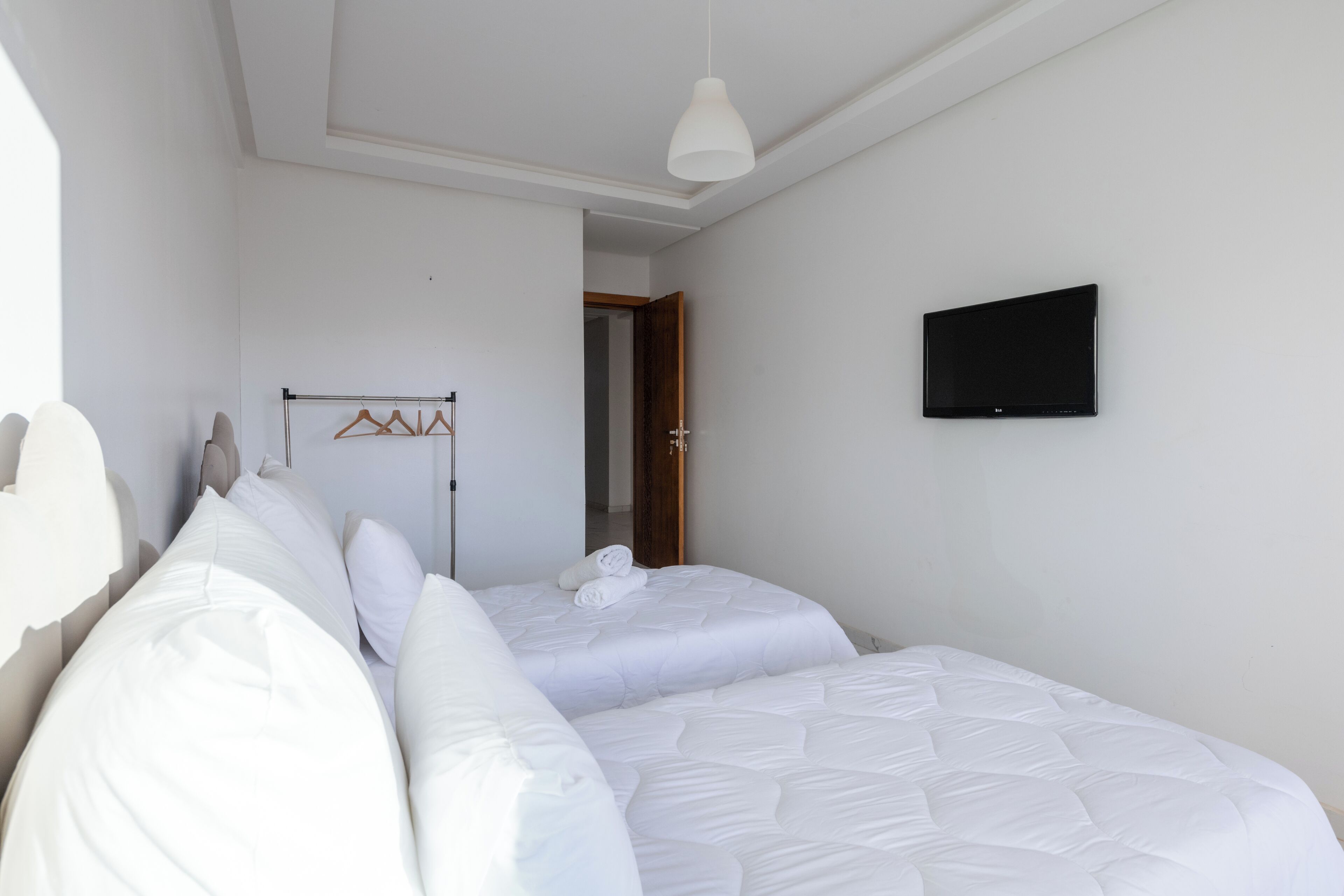 Une chambre avec deux lits, une télévision et un porte-manteau.