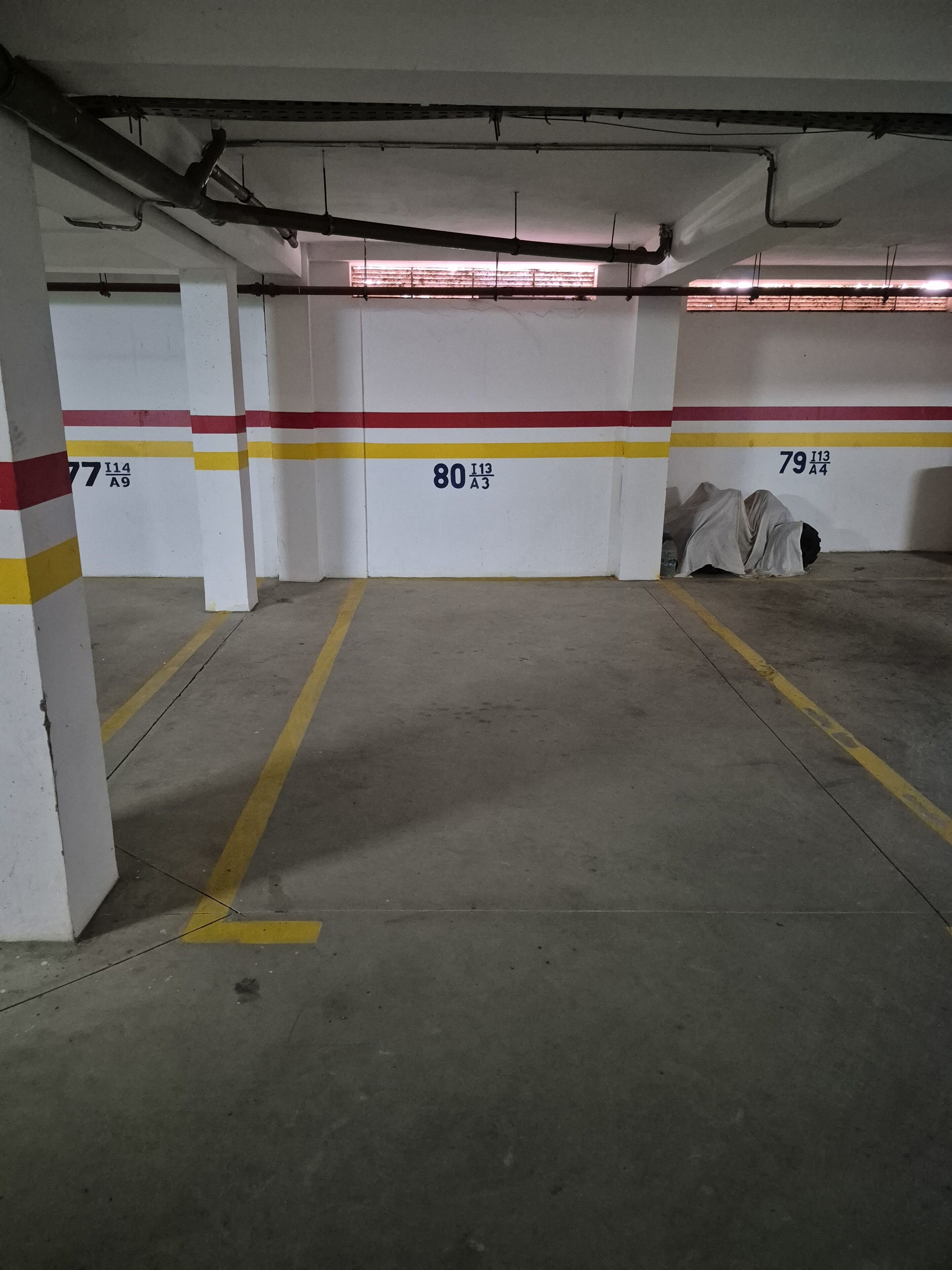 A parking garage with numbered parking spaces, concrete floors, and overhead lighting.