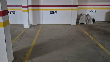 A parking garage with numbered parking spaces, concrete floors, and overhead lighting.