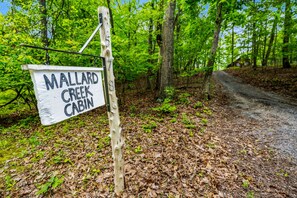 Un letrero de madera con la inscripción 'MALLARD CREEK CABIN', que indica la ubicación de una cabaña.