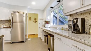 A modern kitchen with stainless steel appliances, white cabinets, and a granite countertop.
