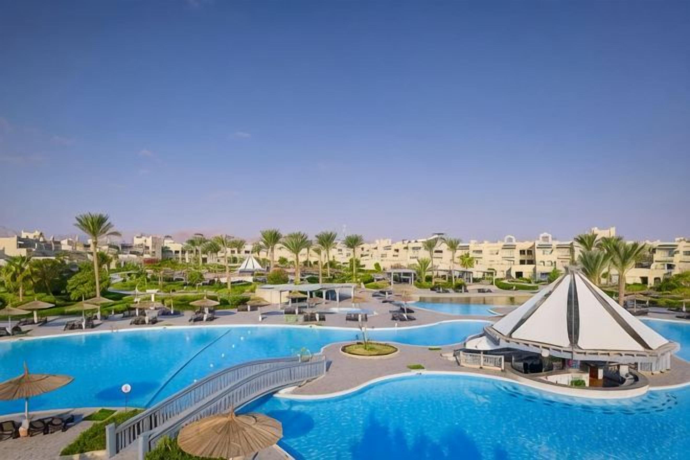 A resort with a large swimming pool, a bridge, and a pavilion.