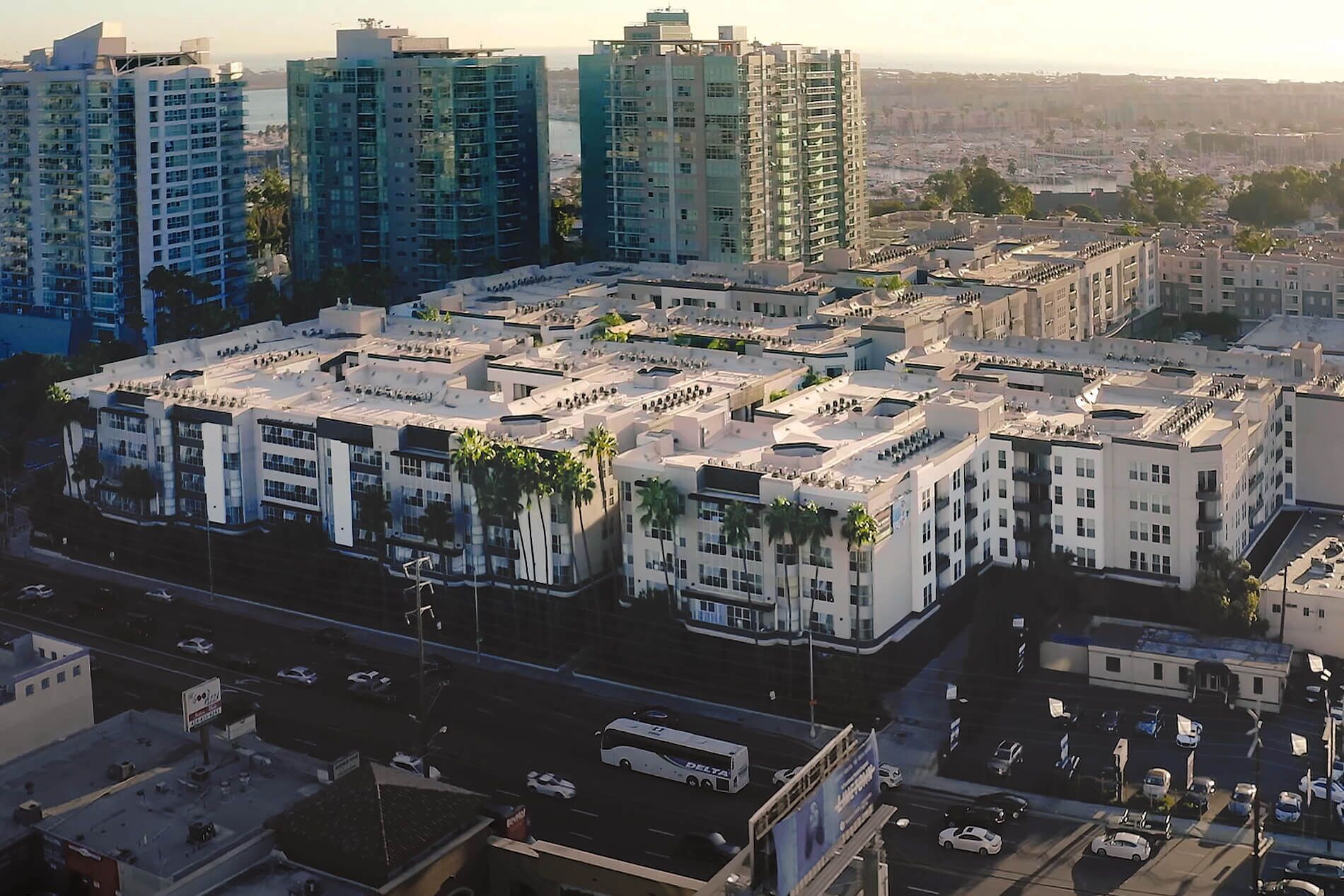 Un complejo de edificios residenciales de gran altura con varios edificios de apartamentos, un patio central y una calle con vehículos.