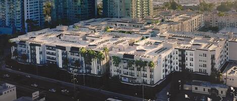 Un complejo de edificios residenciales de gran altura con varios edificios de apartamentos, un patio central y una calle con vehículos.