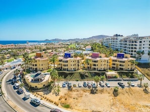 Ein Hotelkomplex an der Küste mit mehreren Gebäuden, einem Parkplatz und Blick auf das Meer.