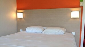 A hotel room with a bed, two wall-mounted lights, and a headboard.