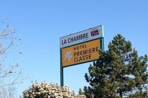 Señal para 'LA CHAMBRE HOTEL PREMIERE CLASSE' con un logotipo y una bandera.