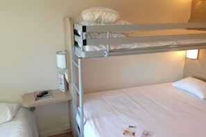 A bunk bed with a pillow on top, a bedside table with a lamp, and a small shelf with items. - Premiere Classe Poitiers Futuroscope - Chasseneuil (Chasseneuil-du-Poitou)