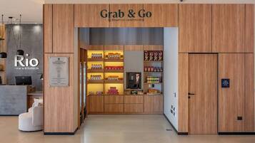 A hotel lobby with a 'Grab & Go' service area, a reception desk, and a 'Rio Hotel by Bourbon' sign.
