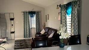 A living room with a sofa, a coffee table, and a dining area with a table and chairs.