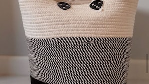 A woven basket with a black and white houndstooth pattern and two black buttons on the top.