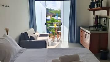 A bedroom with a bed, a sofa, a desk, and a view of the outdoors.