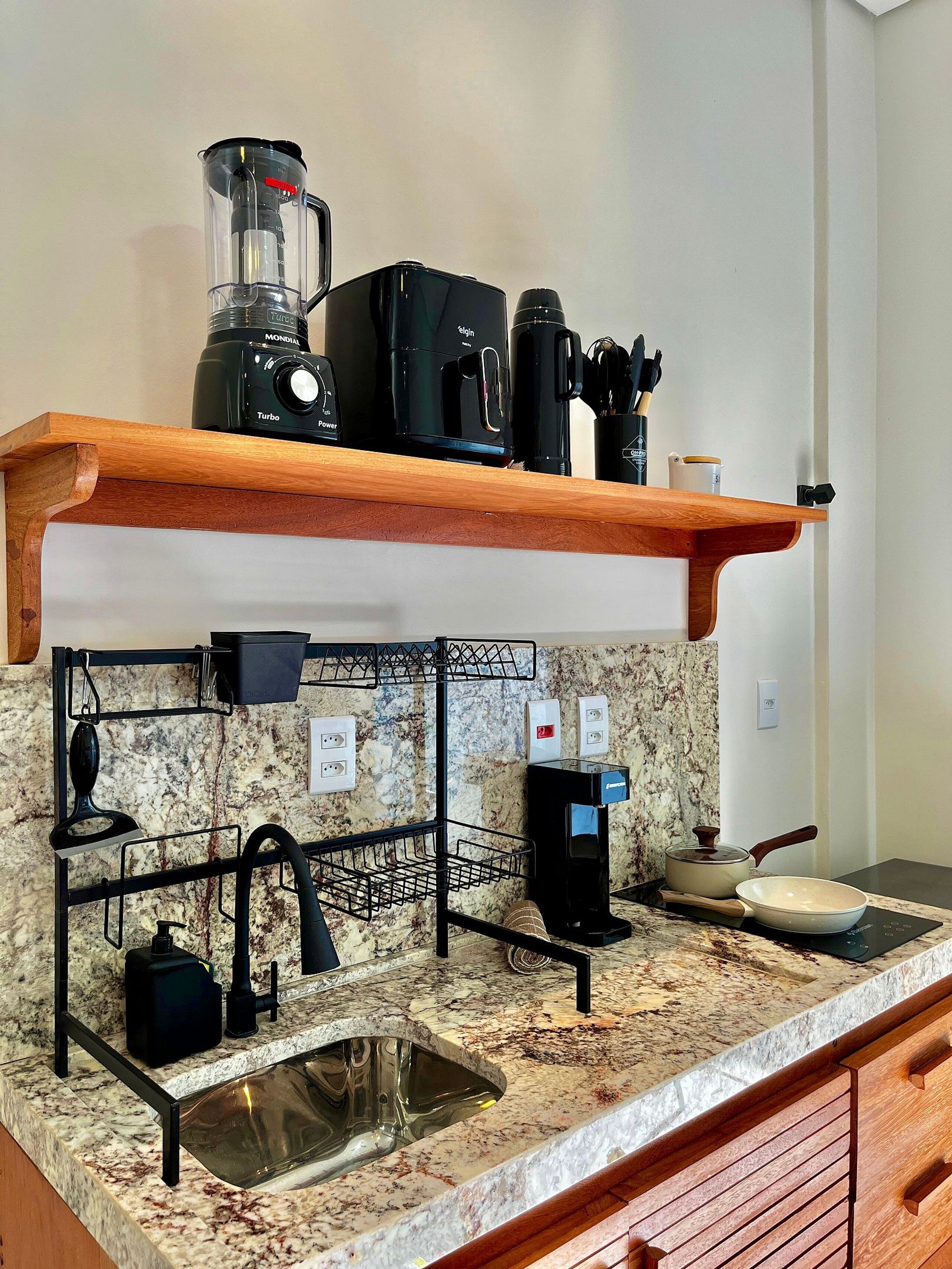 A kitchen with a marble countertop, a coffee maker, a blender, a kettle, and a sink.