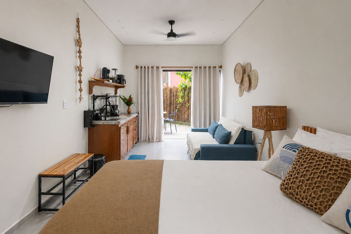 Quarto com cama, escrivaninha, televisão, janela e vista para o exterior.