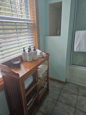 A bathroom with a wooden vanity, a window with blinds, and a towel rack.