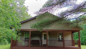 A two-story wooden cabin with a porch, surrounded by trees. - Charming 3-bedroom cottage in Oxford with WiFi and AC close to Wisconson Dells (Oxford)