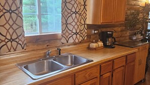 A kitchen with wooden cabinets, a double sink, and a coffee maker. - Charming 3-bedroom cottage in Oxford with WiFi and AC close to Wisconson Dells (Oxford)