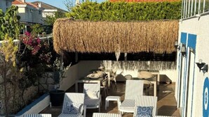 A rooftop terrace with lounge chairs and a thatched roof. - Ambers Alaçatı (Cesme)