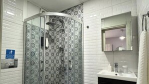 A bathroom with a glass-enclosed shower, a white sink, and a toilet. - Ambers Alaçatı (Cesme)