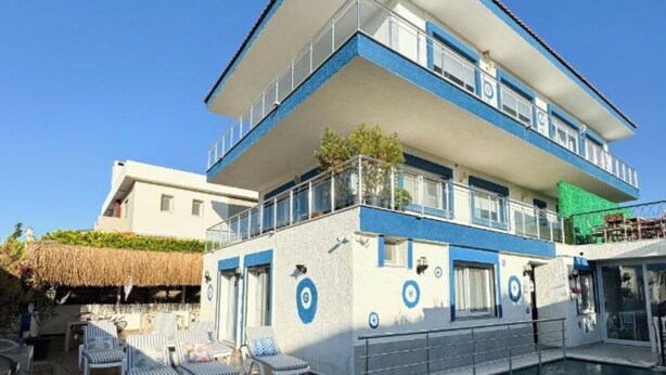 A multi-story hotel with a pool, outdoor seating, and a clear blue sky. - Ambers Alaçatı (Cesme)