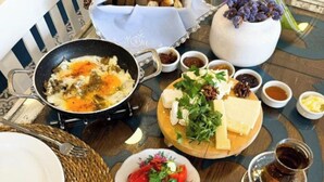 A breakfast setting with a variety of foods including eggs, bread, cheese, and olives. - Ambers Alaçatı (Cesme)
