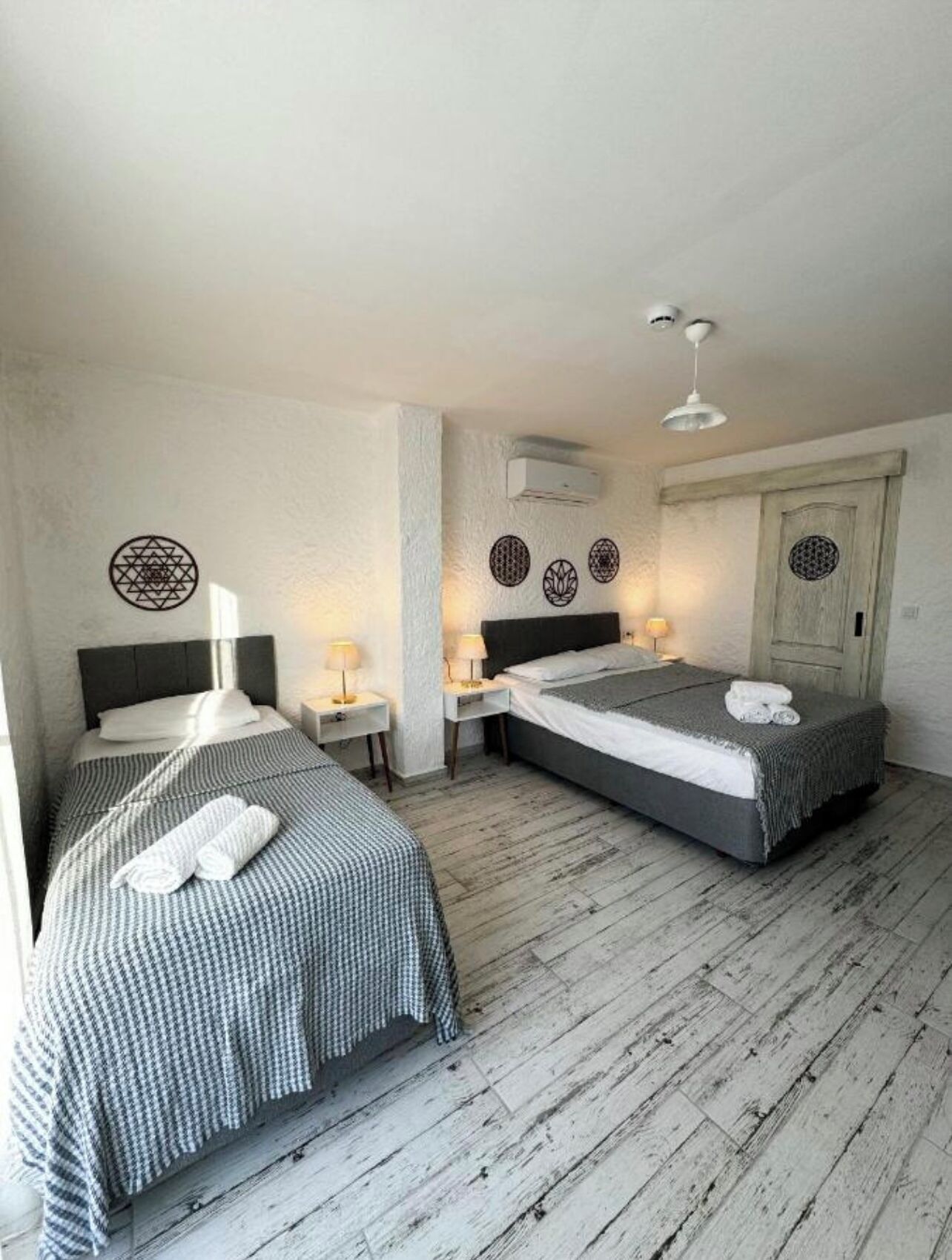 Ein Zimmer mit zwei Betten, Holzboden und weißer Decke.