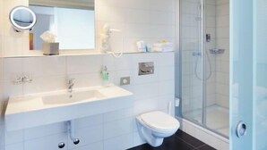 A modern bathroom with a sink, toilet, and glass-enclosed shower. - Hotel Rutli (Zurich)