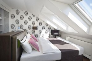 A modern bedroom with a skylight, a bed with pillows, a bedside table, and a TV. - Hotel Rutli (Zurich)