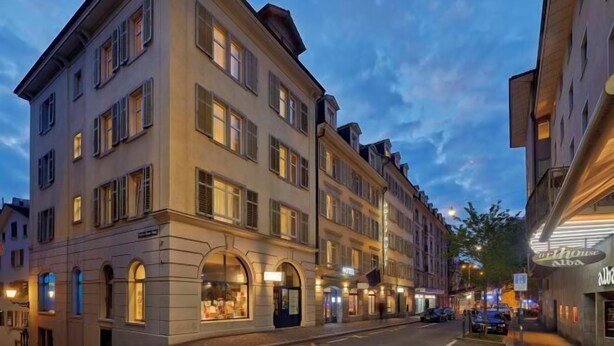 A multi-story hotel with arched windows and a classic facade, located on a city street. - Hotel Rutli (Zurich)