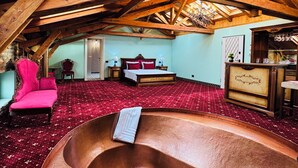 A spacious room with a high ceiling and wooden beams, a large bed with red bedding, a red carpet, and a unique copper bathtub. - JMR Splendor-Private Sauna & Bathtub Sui (Constanta)