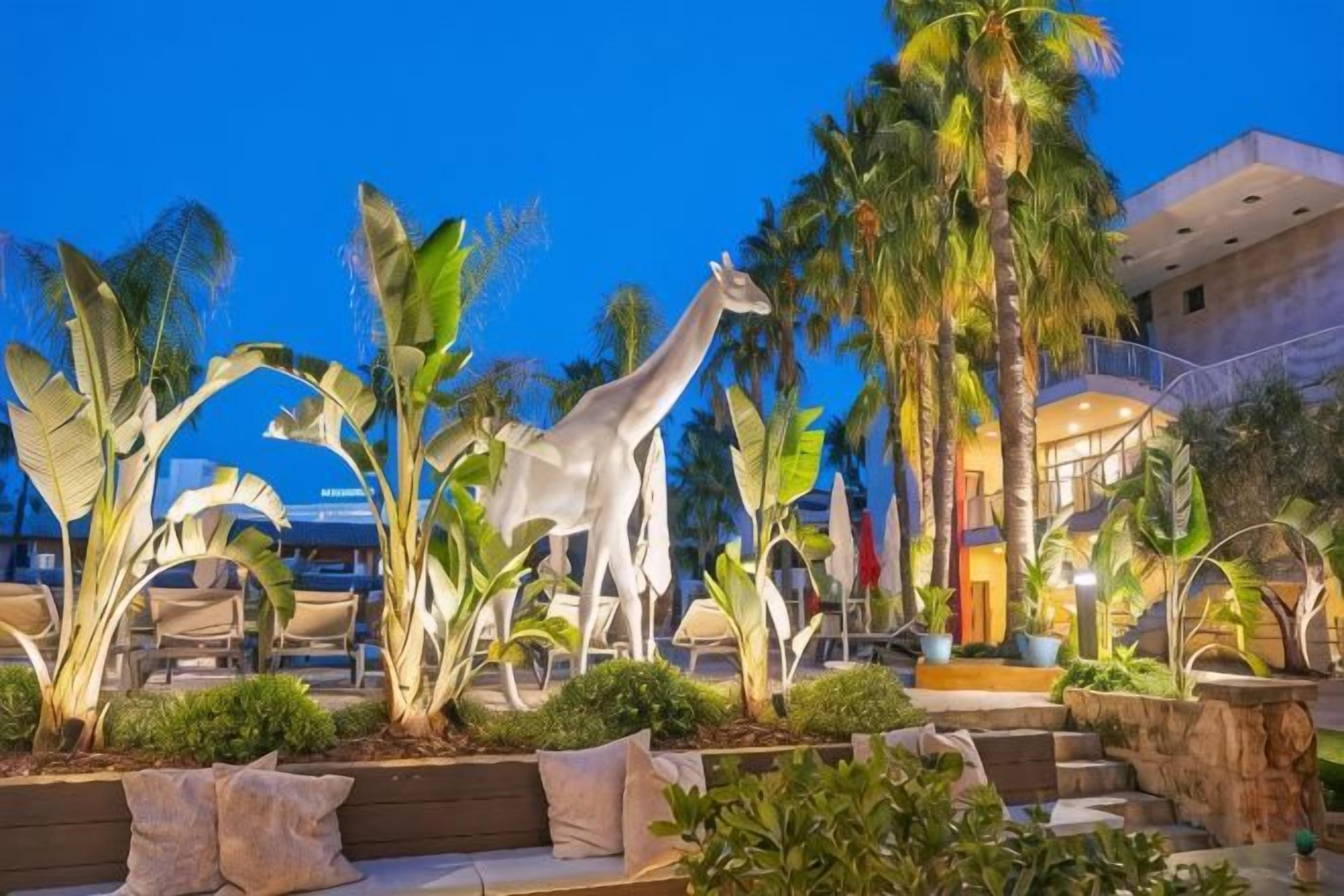 A resort area with a pool, lounge chairs, and a giraffe statue.