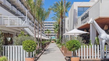 Un pasillo de hotel con una cerca blanca, plantas en macetas y una estatua de jirafa.
