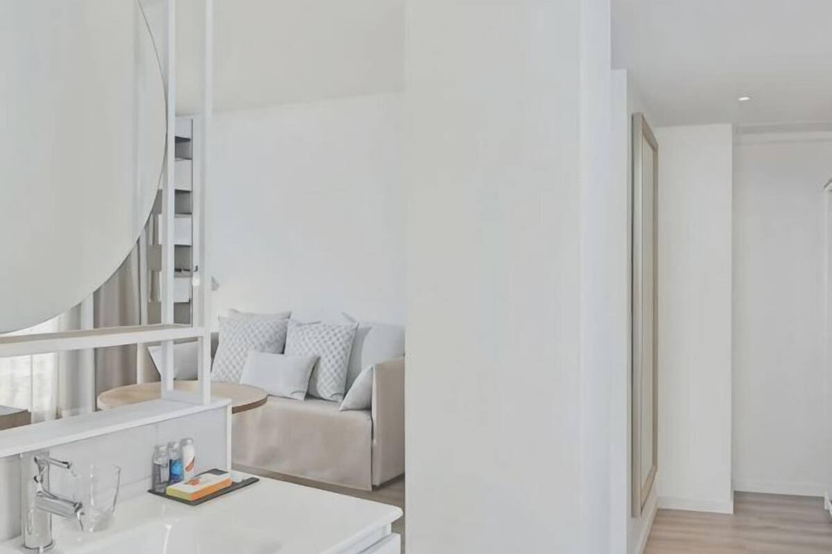 A modern bathroom with a large mirror, a white sink, and a staircase leading to a living area.