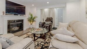 Ein Wohnzimmer mit Kamin, Ledersessel, Sofa und Glastisch.