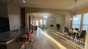A spacious kitchen with a central island, red bar stools, and a dining area with a table and chairs. - Spacious 4 Bed/2 Bath Home in the Woodlands (Spring)