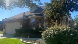 A two-story house with a garage, surrounded by well-maintained lawns and bushes. - Spacious 4 Bed/2 Bath Home in the Woodlands (Spring)