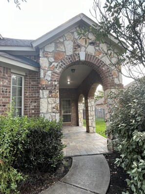 A stone and brick house with a covered porch and a pathway leading to the entrance. - Spacious 4 Bed/2 Bath Home in the Woodlands (Spring)
