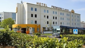 Un immeuble abritant un hôtel, avec plusieurs étages, une entrée imposante et un arrêt de bus à proximité.