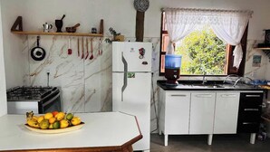 Une cuisine équipée d’une cuisinière à gaz, d’un réfrigérateur, d’un évier et d’une fenêtre avec des rideaux.