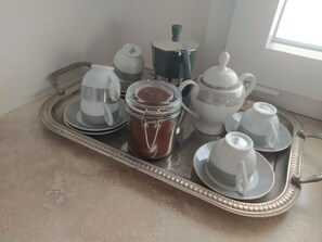 A tray with a coffee maker, a jar of coffee, and several cups and saucers.