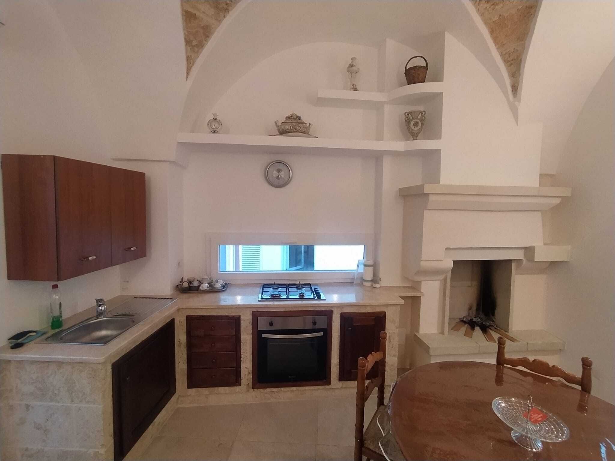 Una cucina compatta con fornelli a gas, forno e zona pranzo con tavolo e sedie.