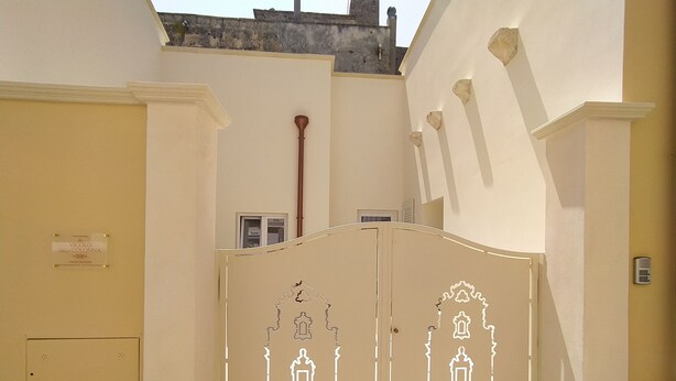 A gated entrance with decorative white patterns, a clear sign, and a visible water pipe.