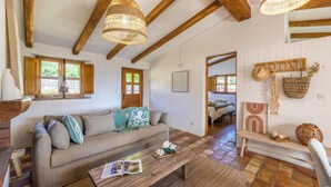 A cozy living room with a sofa, wooden beams, and a hanging light fixture. - Charming sheepfold with private heated pool between sea and mountains (Sotta)