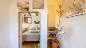 A bedroom with a bed, bedside table, lamp, and wall-mounted decor. - Charming sheepfold with private heated pool between sea and mountains (Sotta)